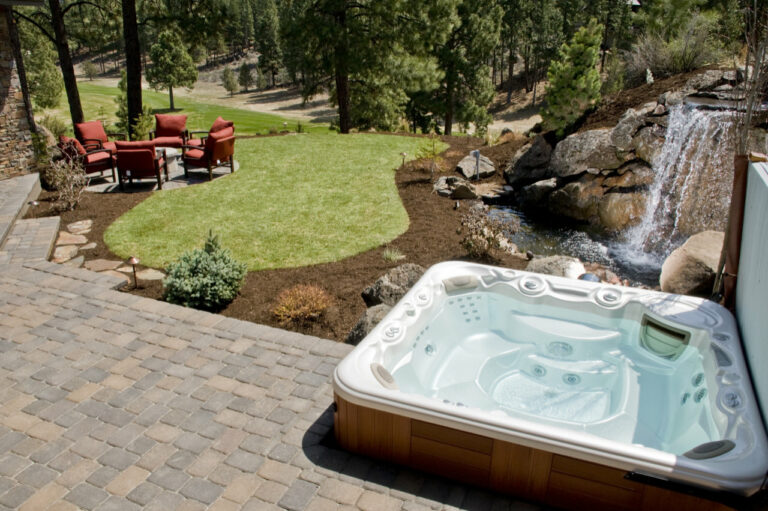 Hot tub on patio near large waterfall and seating area Hot Tub tiled with storage area/seating